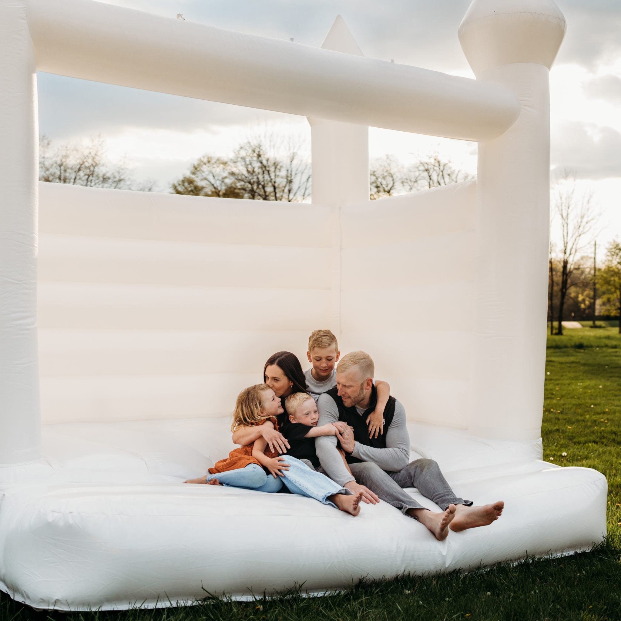 outdoor photo of Classic Bounce owners and children sitting in a bounce house.